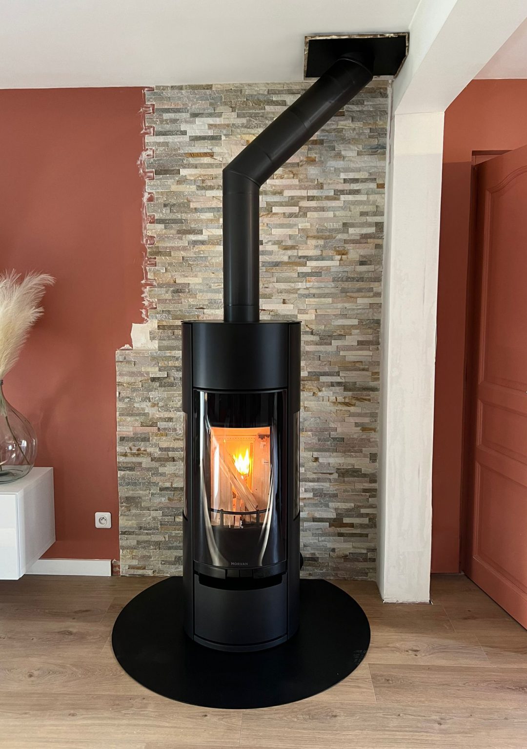 Poêle à bois Vision'R noir de Morvan, offrant une puissance de 6 à 6,4 kW et un rendement de 77 %. Il dispose d'une conception élégante avec une chambre de combustion cylindrique, et des vitres offrant une vision intégrale des flammes. Idéal pour un chauffage performant et écologique avec certification Flamme Verte.