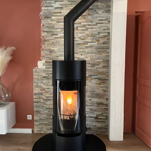 Poêle à bois Vision'R noir de Morvan, offrant une puissance de 6 à 6,4 kW et un rendement de 77 %. Il dispose d'une conception élégante avec une chambre de combustion cylindrique, et des vitres offrant une vision intégrale des flammes. Idéal pour un chauffage performant et écologique avec certification Flamme Verte.